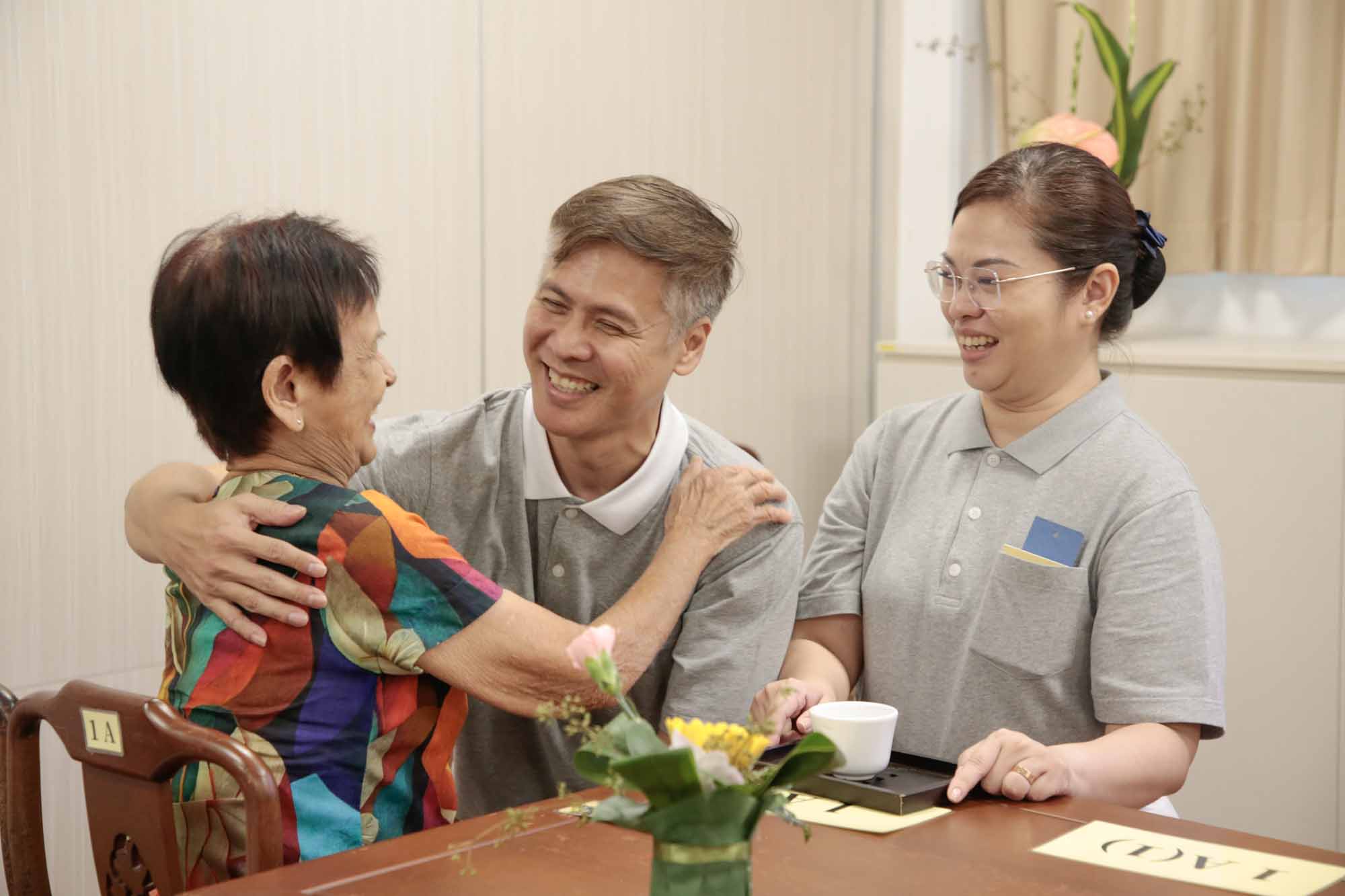 林文利（左）、梁丽英（右）夫妻俩带着母亲与孩子参与奉茶尽孝，母子相拥传递温情。摄/ 冯桂琼