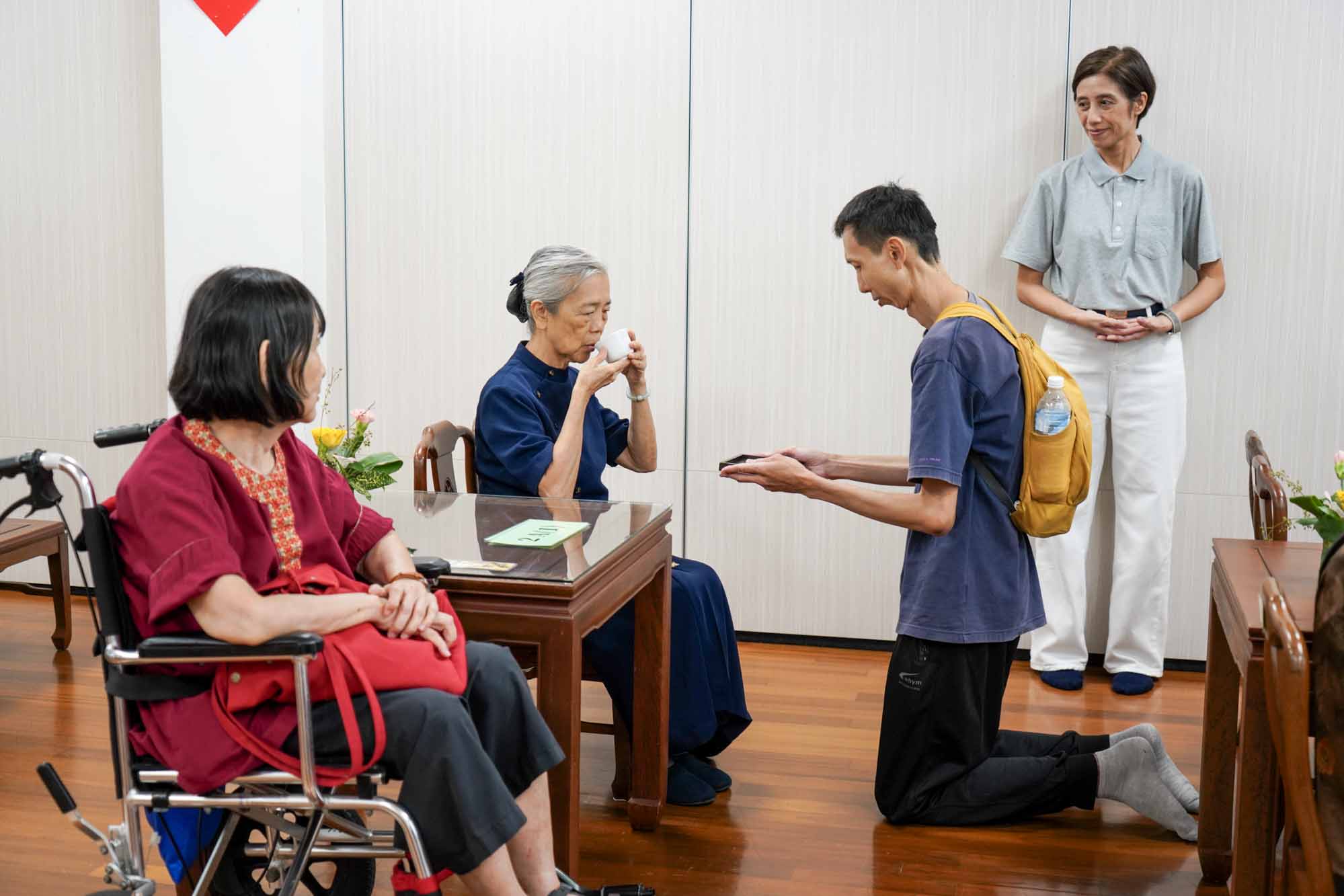 李文川（右）向母亲高秀英（坐轮椅者）和阿姨高美英奉茶。摄/ 曾美珍