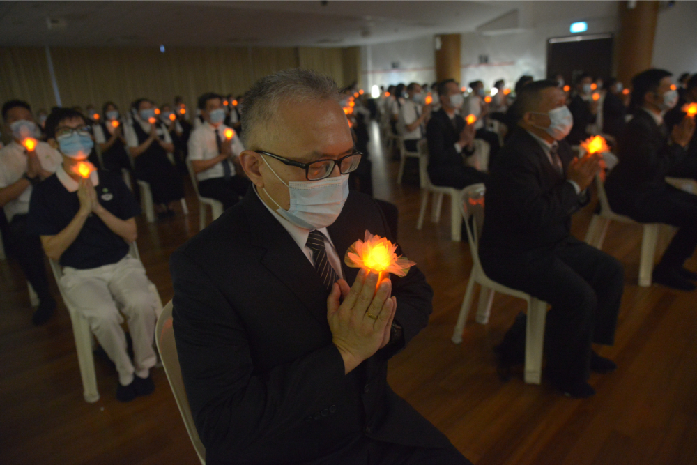 Volunteers hold the lotus lamps in their hands as they sing the song “Prayer” to pray for blessings and peace for all in the world. (Photo by Pua Poo Toong) 
