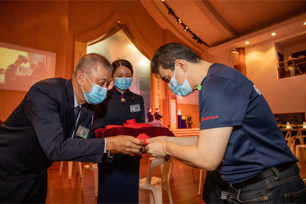 Public members respectfully receive the red packet of wisdom and blessings from Tzu Chi commissioners, signifying the receipt of Master Cheng Yen’s blessing from Taiwan. (Photo by Khor Kim Seng) 